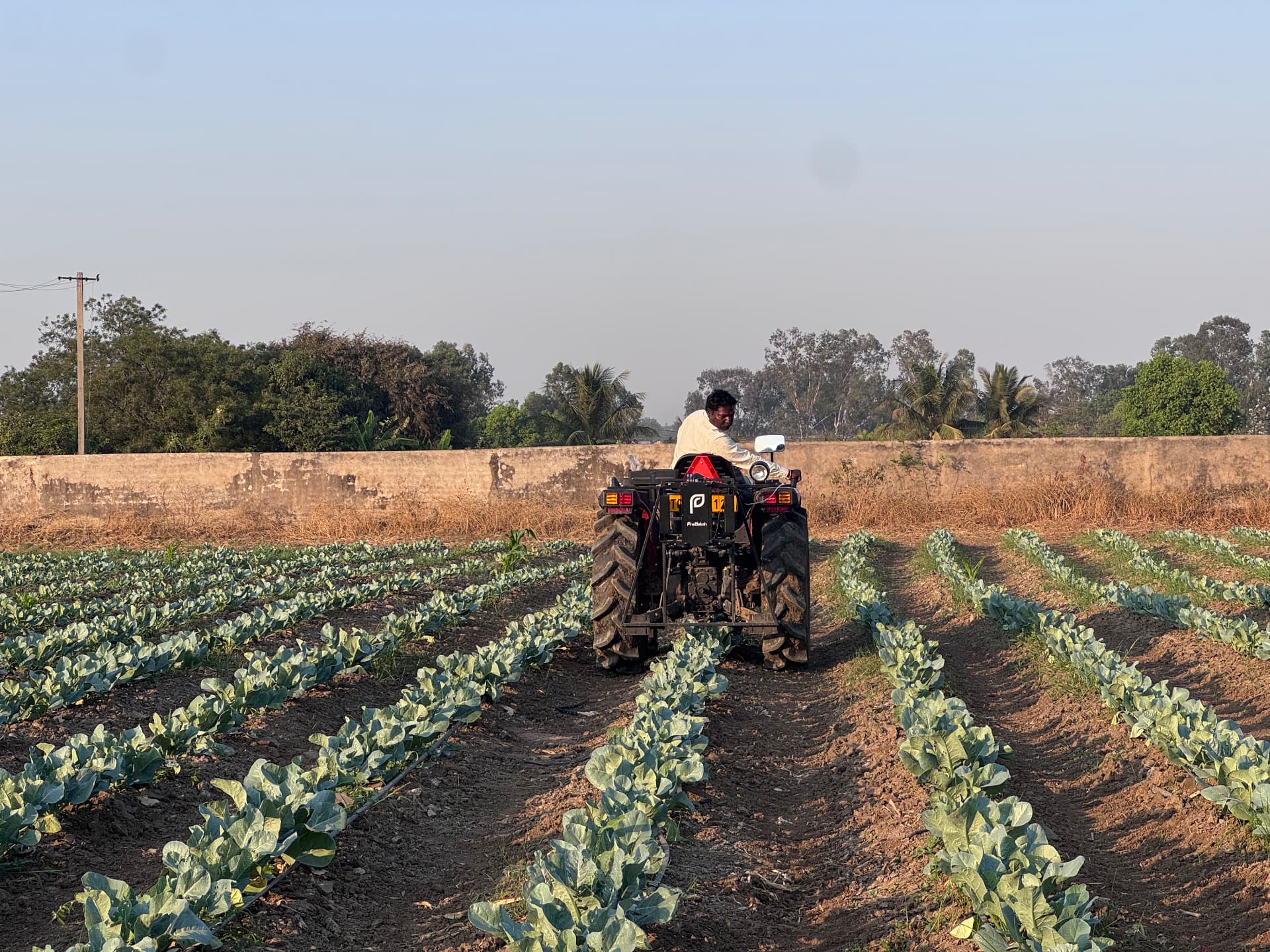 Two engineers testing the Rakshakh machine on a tractor in the field