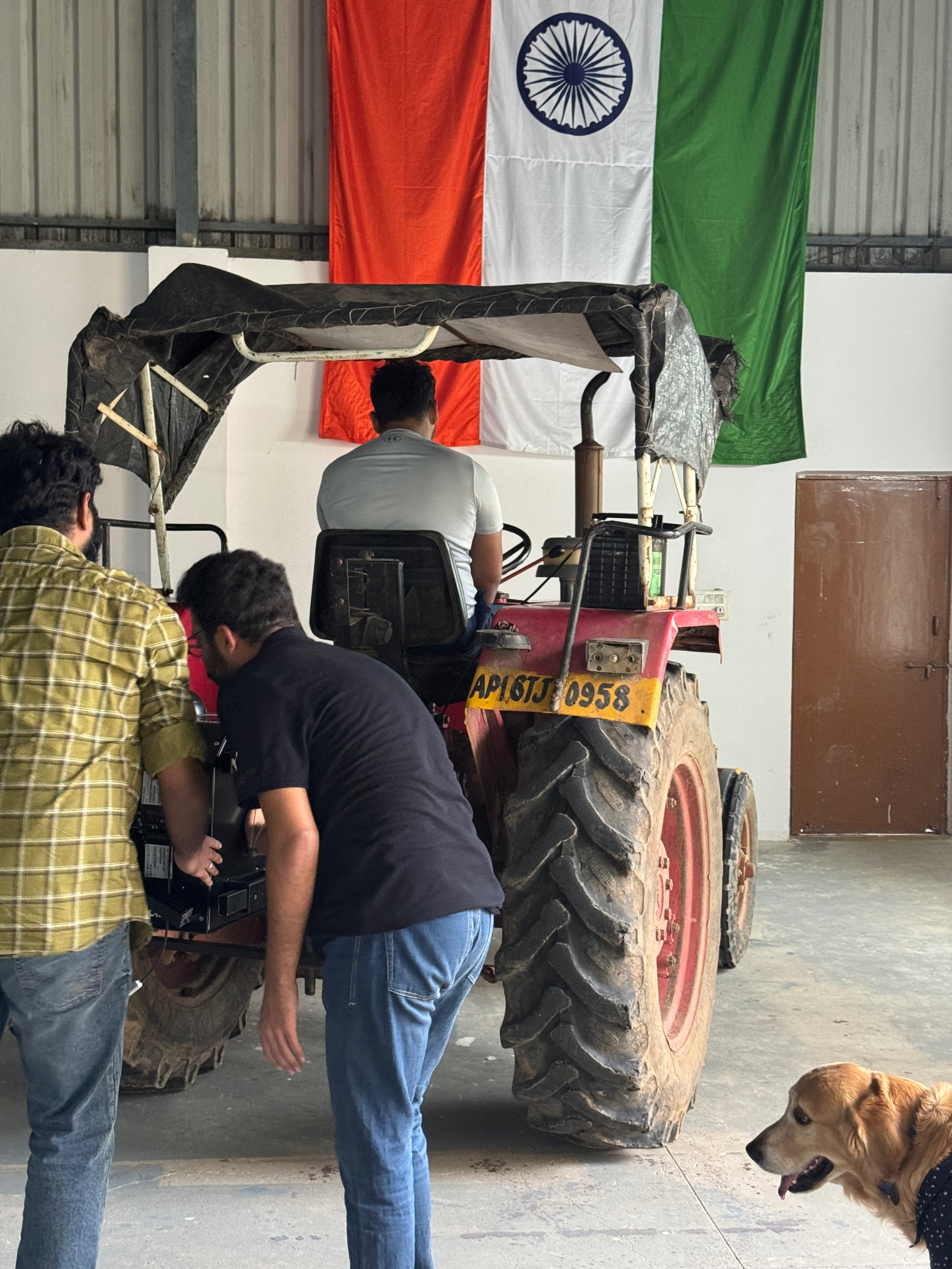 The Harvested Robotics team working on a tractor in front of the Indian flag